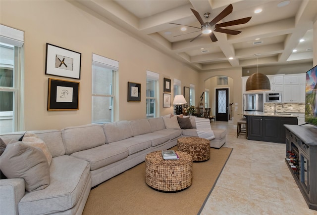 living room with ceiling fan, beamed ceiling, recessed lighting, arched walkways, and coffered ceiling