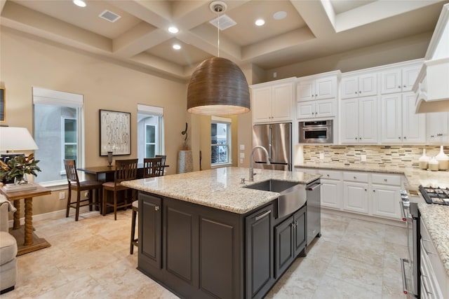 kitchen with a sink, coffered ceiling, tasteful backsplash, white cabinetry, and appliances with stainless steel finishes