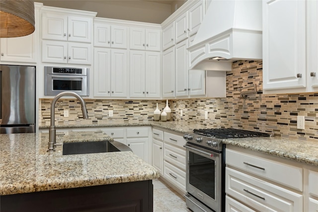 kitchen featuring backsplash, custom range hood, stainless steel appliances, white cabinetry, and a sink