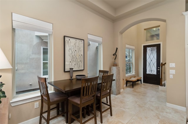 dining room featuring baseboards, arched walkways, and a high ceiling