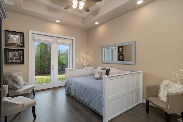 bedroom with access to exterior, dark wood-style flooring, and a tray ceiling