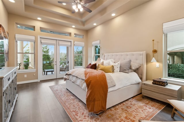 bedroom with a tray ceiling, french doors, a high ceiling, wood finished floors, and access to outside