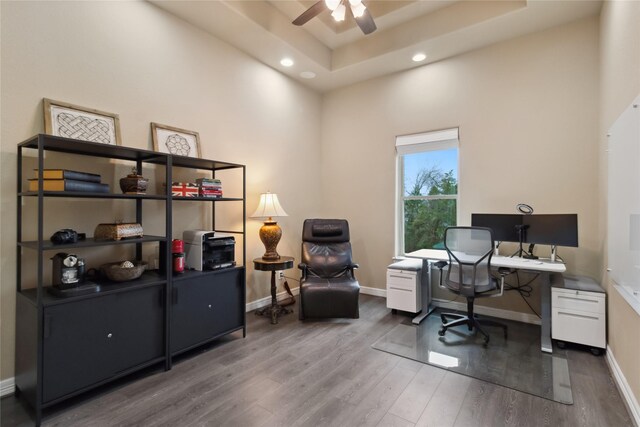 home office with baseboards, a raised ceiling, wood finished floors, and a ceiling fan