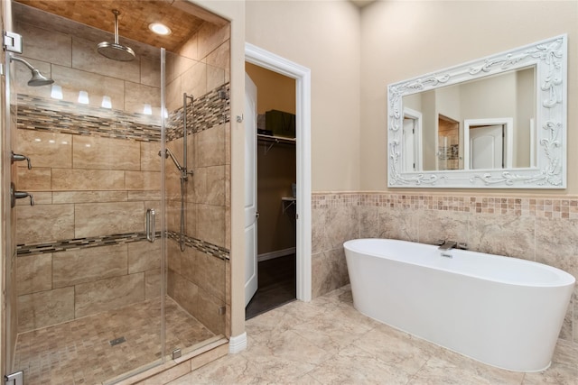 full bathroom featuring wainscoting, a freestanding bath, a stall shower, and a spacious closet