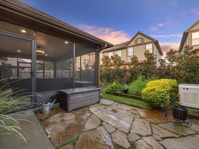 patio terrace at dusk featuring a sunroom