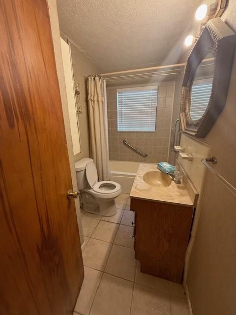 full bathroom featuring vanity, toilet, tile patterned floors, a textured ceiling, and shower / bath combo with shower curtain