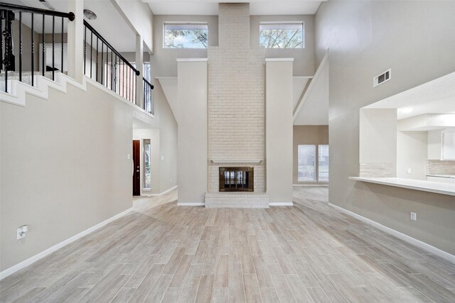 unfurnished living room featuring a brick fireplace and light wood-type flooring