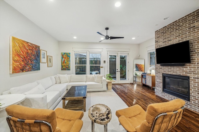 living room featuring dark hardwood / wood-style flooring, a brick fireplace, french doors, and ceiling fan