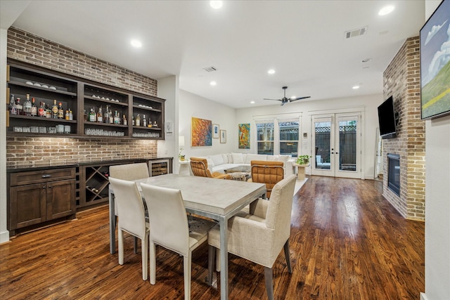 dining area featuring dark wood-type flooring, french doors, bar area, brick wall, and a fireplace