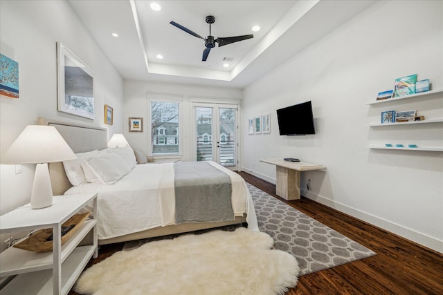 bedroom featuring access to exterior, dark hardwood / wood-style floors, a raised ceiling, and ceiling fan