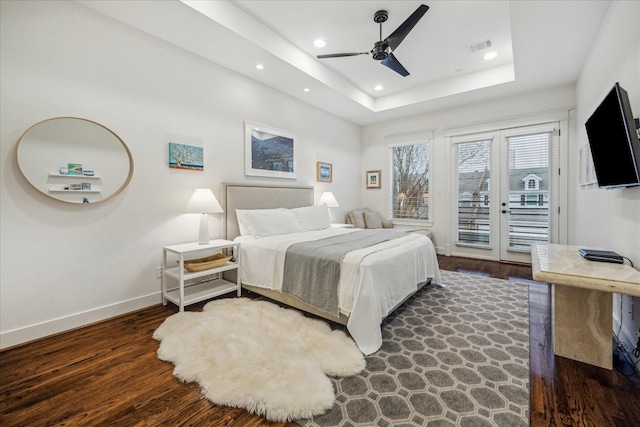 bedroom featuring access to exterior, dark wood-type flooring, a raised ceiling, and ceiling fan