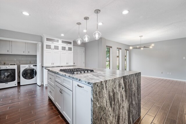 kitchen featuring washer and dryer, white cabinets, hanging light fixtures, stainless steel gas cooktop, and light stone countertops