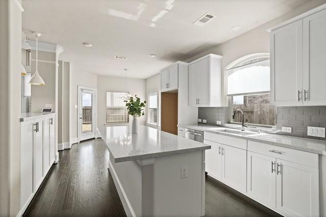 kitchen with sink, white cabinetry, dishwasher, pendant lighting, and light stone countertops