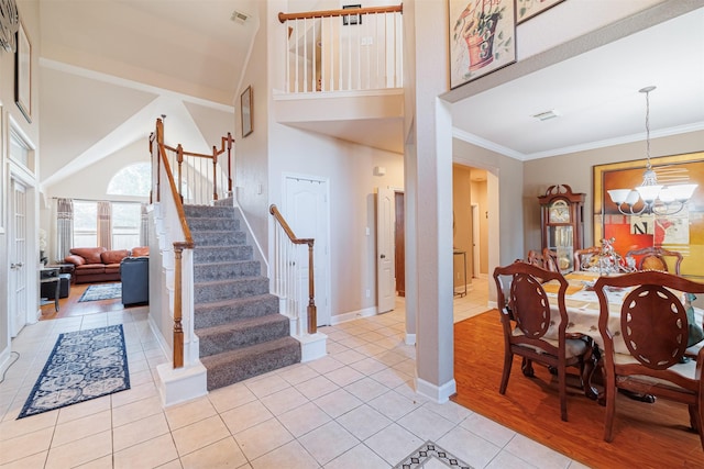 tiled foyer with an inviting chandelier, ornamental molding, and a high ceiling