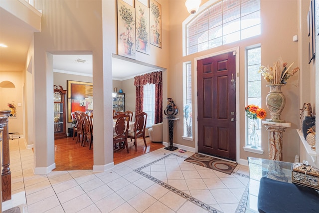 tiled entryway featuring a high ceiling and crown molding