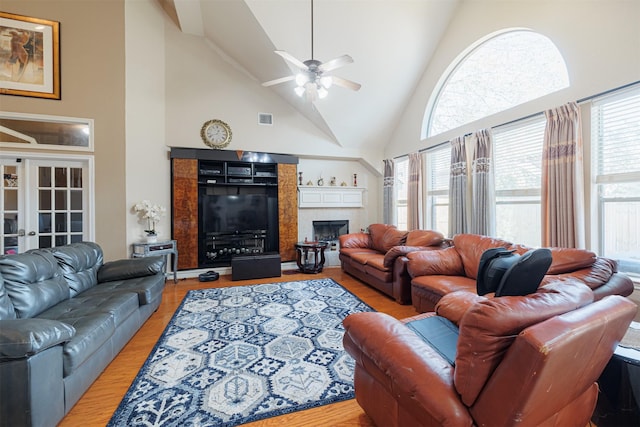 living room featuring a tiled fireplace, high vaulted ceiling, and light hardwood / wood-style floors