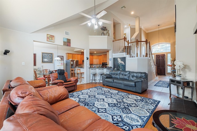 living room with hardwood / wood-style floors, crown molding, high vaulted ceiling, and ceiling fan