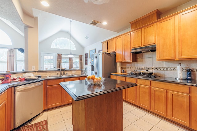 kitchen with vaulted ceiling, a kitchen island, light tile patterned flooring, sink, and stainless steel appliances