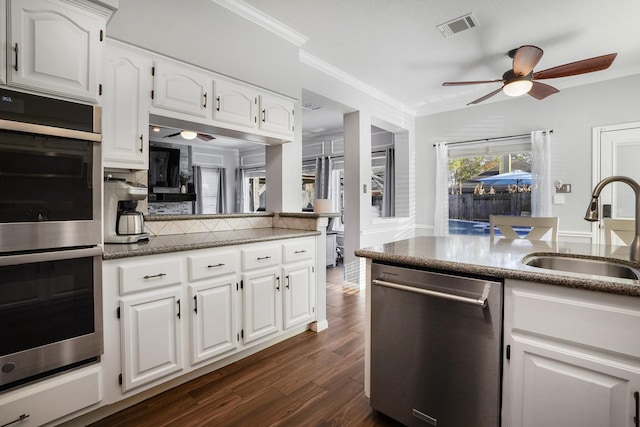 kitchen with white cabinetry, ornamental molding, stainless steel appliances, and sink