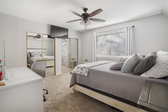 bedroom with multiple closets, ceiling fan, light carpet, and a textured ceiling