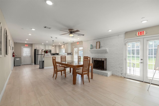 dining area with ceiling fan, a fireplace, and french doors