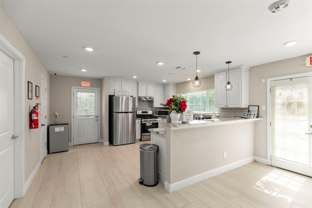 kitchen with decorative light fixtures, kitchen peninsula, stainless steel appliances, decorative backsplash, and white cabinets