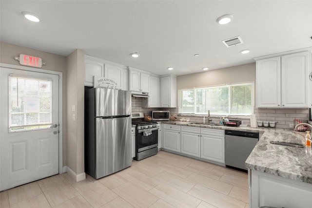 kitchen featuring light stone countertops, white cabinetry, appliances with stainless steel finishes, and sink