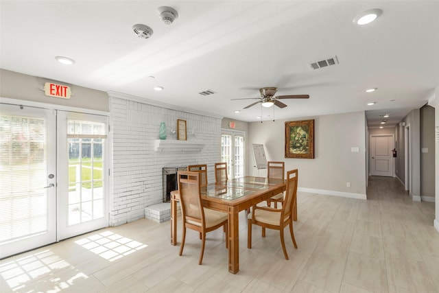 dining room with a fireplace, french doors, ceiling fan, and brick wall