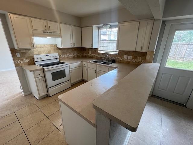 kitchen with sink, white cabinets, decorative backsplash, white electric range oven, and kitchen peninsula