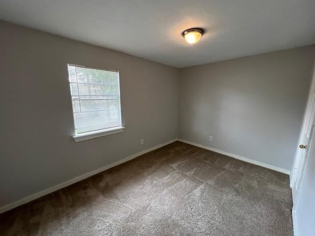 unfurnished room featuring dark colored carpet