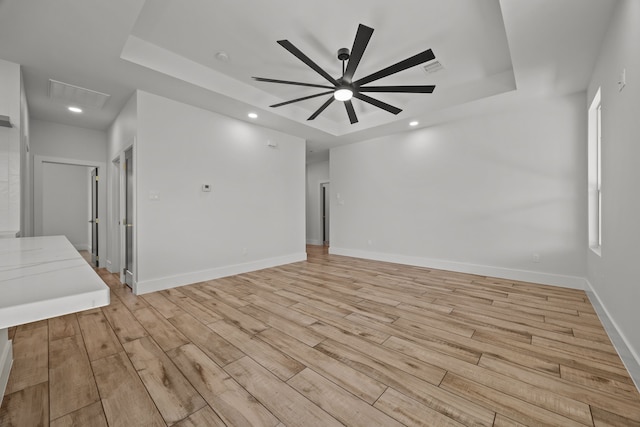 spare room with ceiling fan, a raised ceiling, and light hardwood / wood-style flooring