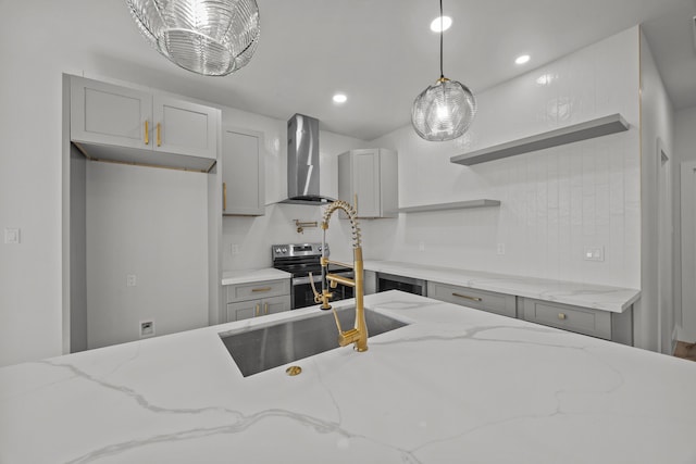 kitchen with wall chimney exhaust hood, sink, gray cabinets, pendant lighting, and light stone countertops