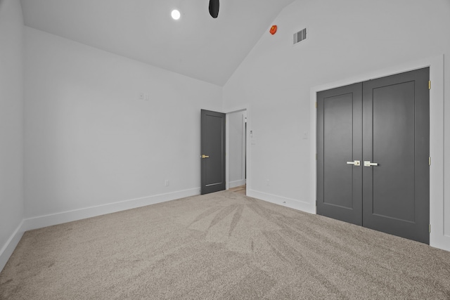 unfurnished bedroom with ceiling fan, carpet, high vaulted ceiling, and a closet