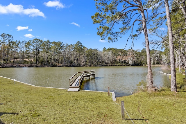 view of dock with a lawn and a water view