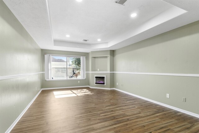 unfurnished living room with dark wood-type flooring and a tray ceiling