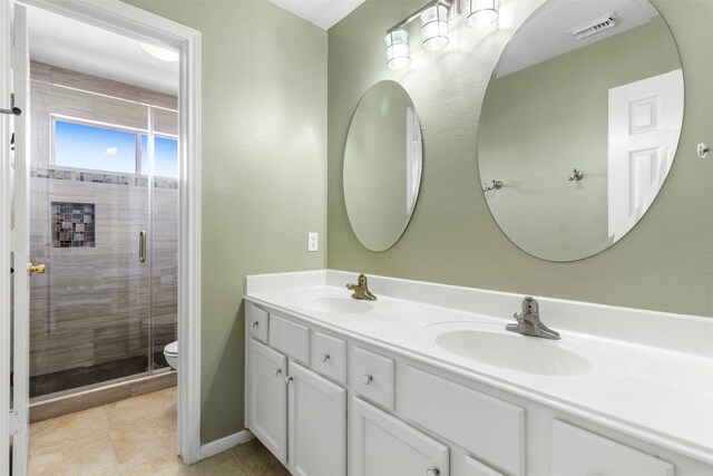 bathroom featuring tile patterned flooring, vanity, a shower with shower door, and toilet