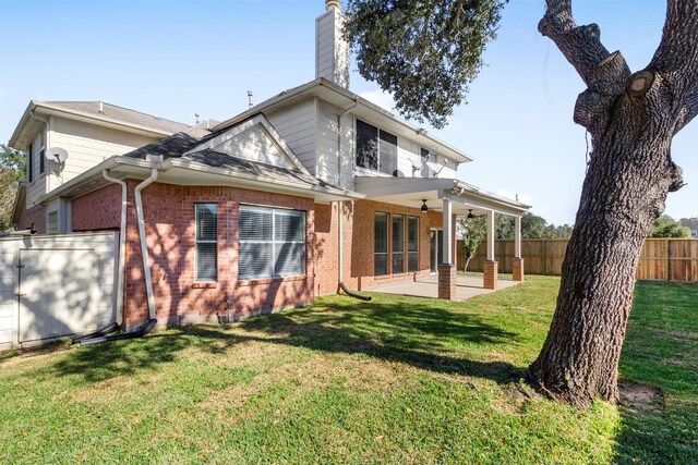 rear view of house with ceiling fan, a patio, and a lawn