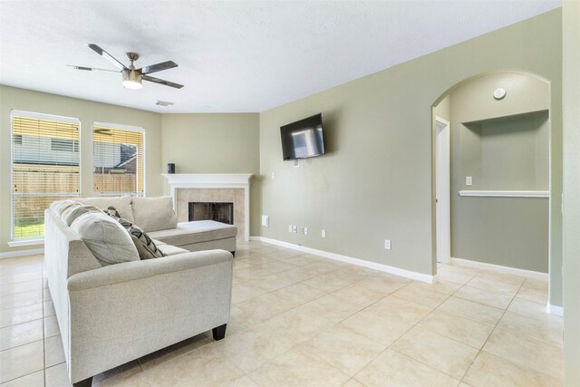 living room featuring light tile patterned floors, a textured ceiling, a tile fireplace, and ceiling fan