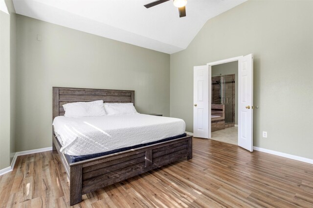 bedroom featuring vaulted ceiling, ceiling fan, light hardwood / wood-style floors, and ensuite bath