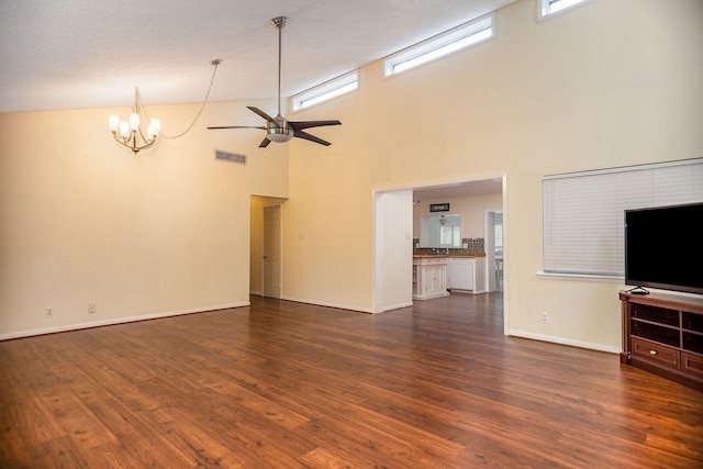 unfurnished living room with lofted ceiling, ceiling fan with notable chandelier, and dark wood-type flooring