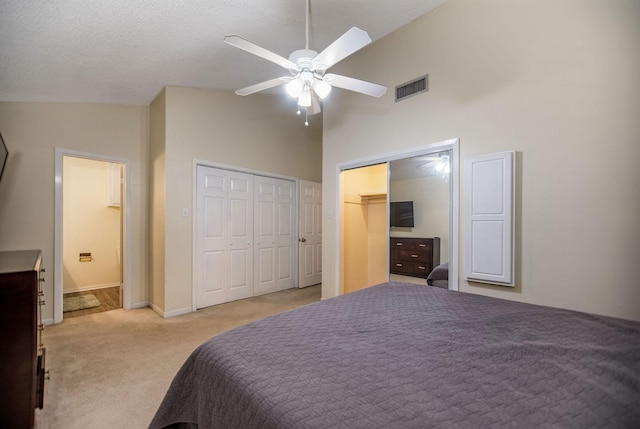 bedroom with ensuite bath, ceiling fan, high vaulted ceiling, light colored carpet, and multiple closets