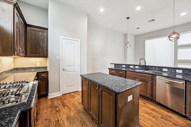 kitchen with stainless steel appliances, hanging light fixtures, sink, and a kitchen island