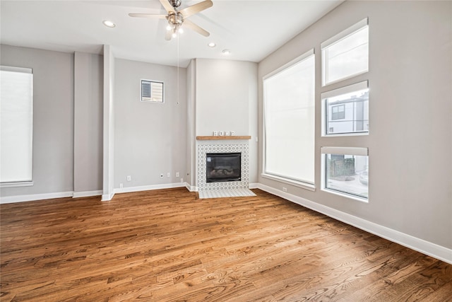 unfurnished living room featuring ceiling fan, a fireplace, and light hardwood / wood-style flooring