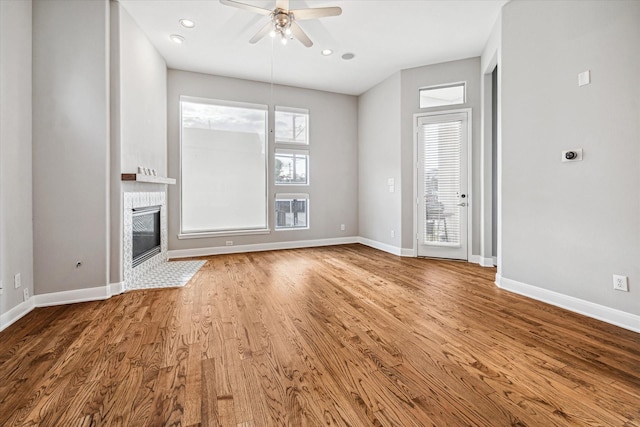 unfurnished living room featuring ceiling fan, heating unit, hardwood / wood-style floors, and a fireplace