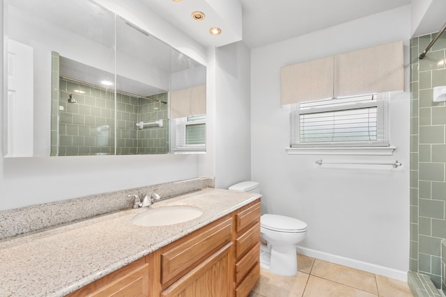 bathroom with a tile shower, vanity, tile patterned flooring, and toilet