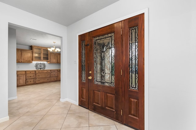 tiled foyer entrance with a textured ceiling and a chandelier