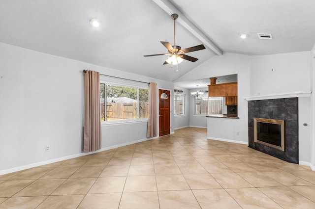 unfurnished living room with a tiled fireplace, light tile patterned floors, ceiling fan with notable chandelier, and vaulted ceiling with beams