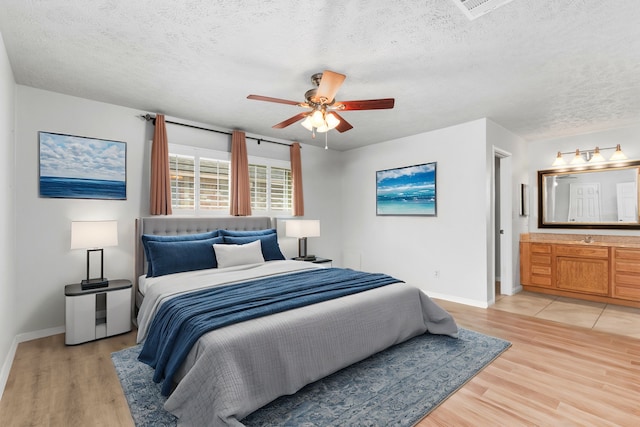 bedroom with ensuite bathroom, ceiling fan, a textured ceiling, and light wood-type flooring