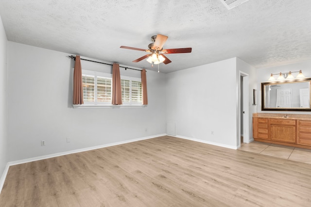 interior space with sink, ensuite bath, light hardwood / wood-style flooring, and a textured ceiling