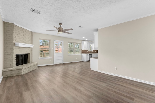 unfurnished living room with a brick fireplace, visible vents, and dark wood-type flooring